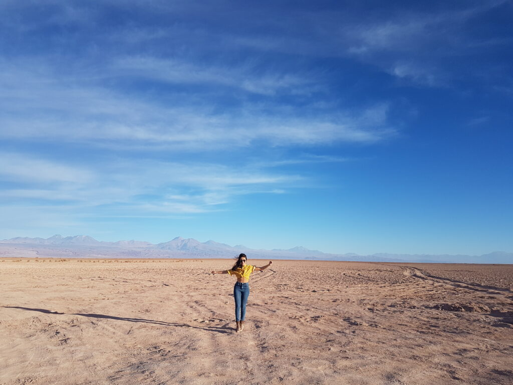 moça andando com os braços abertos no deserto