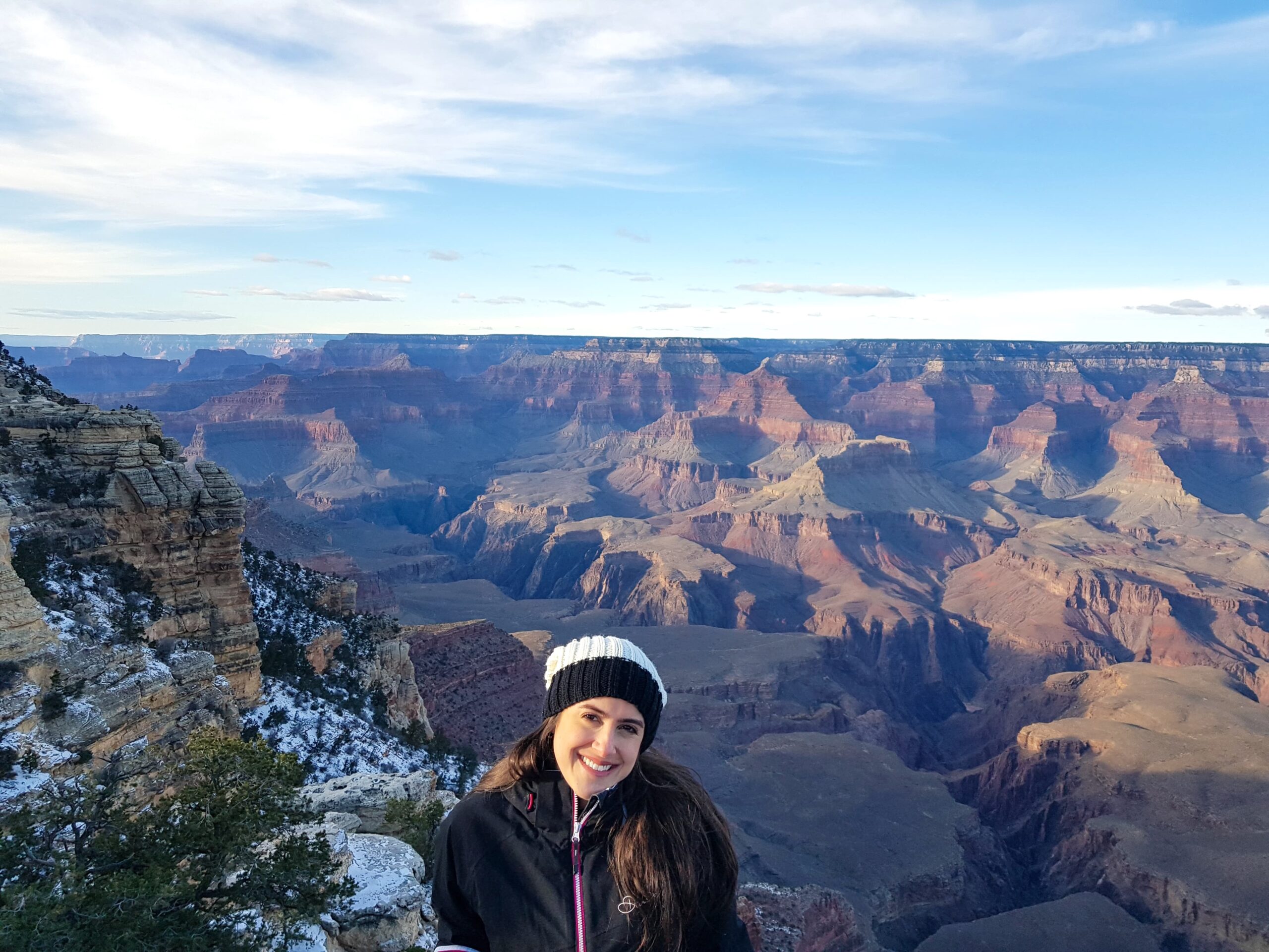 Mulher sorrindo e ao fundo ampla paisagem do Grand Canyon