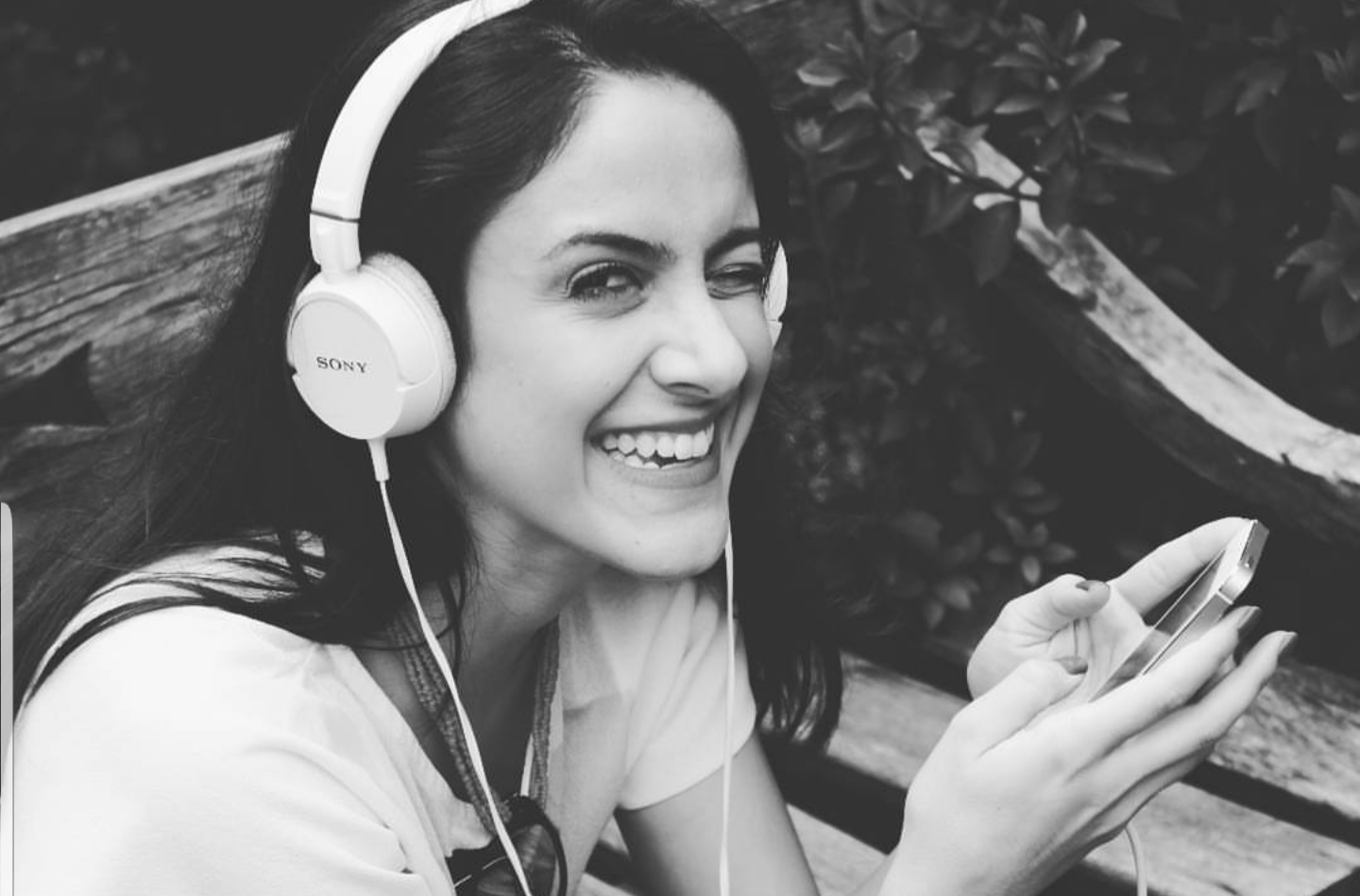 Mulher ouvindo podcast no fone e sorrindo