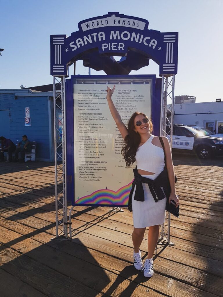 Mulher em frente à placa do Pier de Santa Mônica - Califórnia